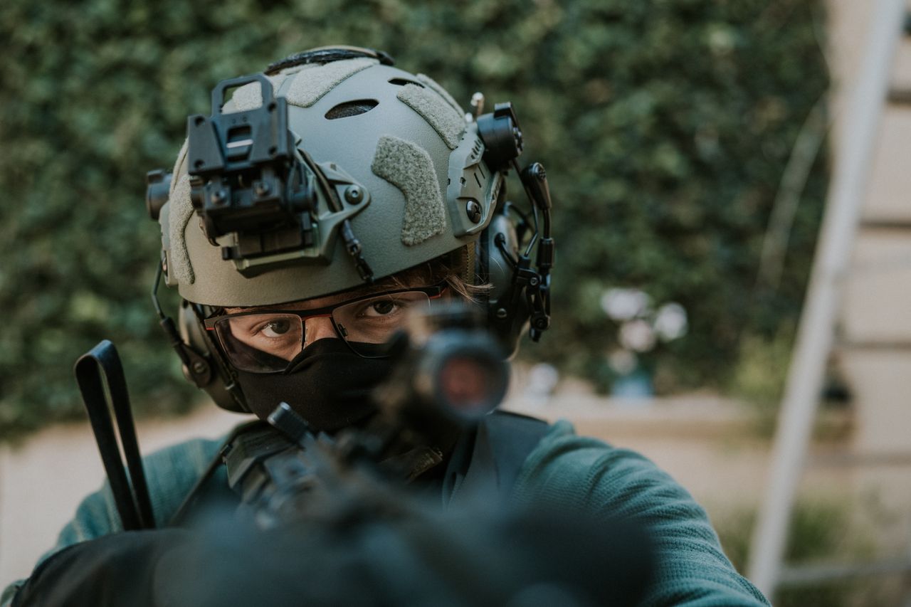 Close-up of a soldier in tactical gear aiming with precision outdoors.